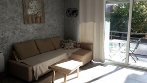 Un salon comprenant un canapé, une table basse, une décoration murale représentant une carte du monde et une porte-fenêtre coulissante donnant sur un balcon.