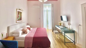 A bedroom with a bed, bedside table, desk, and a television. - Boutique Apartment in Old Town (Napoli)