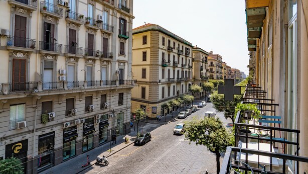 A street view with multi-story buildings, a cobblestone street, and a few parked cars. - Boutique Apartment in Old Town (Napoli)