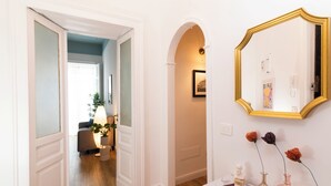 A hallway with a white door, a mirror, and a console table with vases. - Boutique Apartment in Old Town (Napoli)