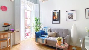 A living room with a sofa, a coffee table, a chair, a plant, and framed pictures on the wall. - Boutique Apartment in Old Town (Napoli)