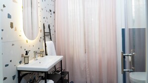 A bathroom with a white sink, a mirror, and a shower curtain. - Boutique Apartment in Old Town (Napoli)