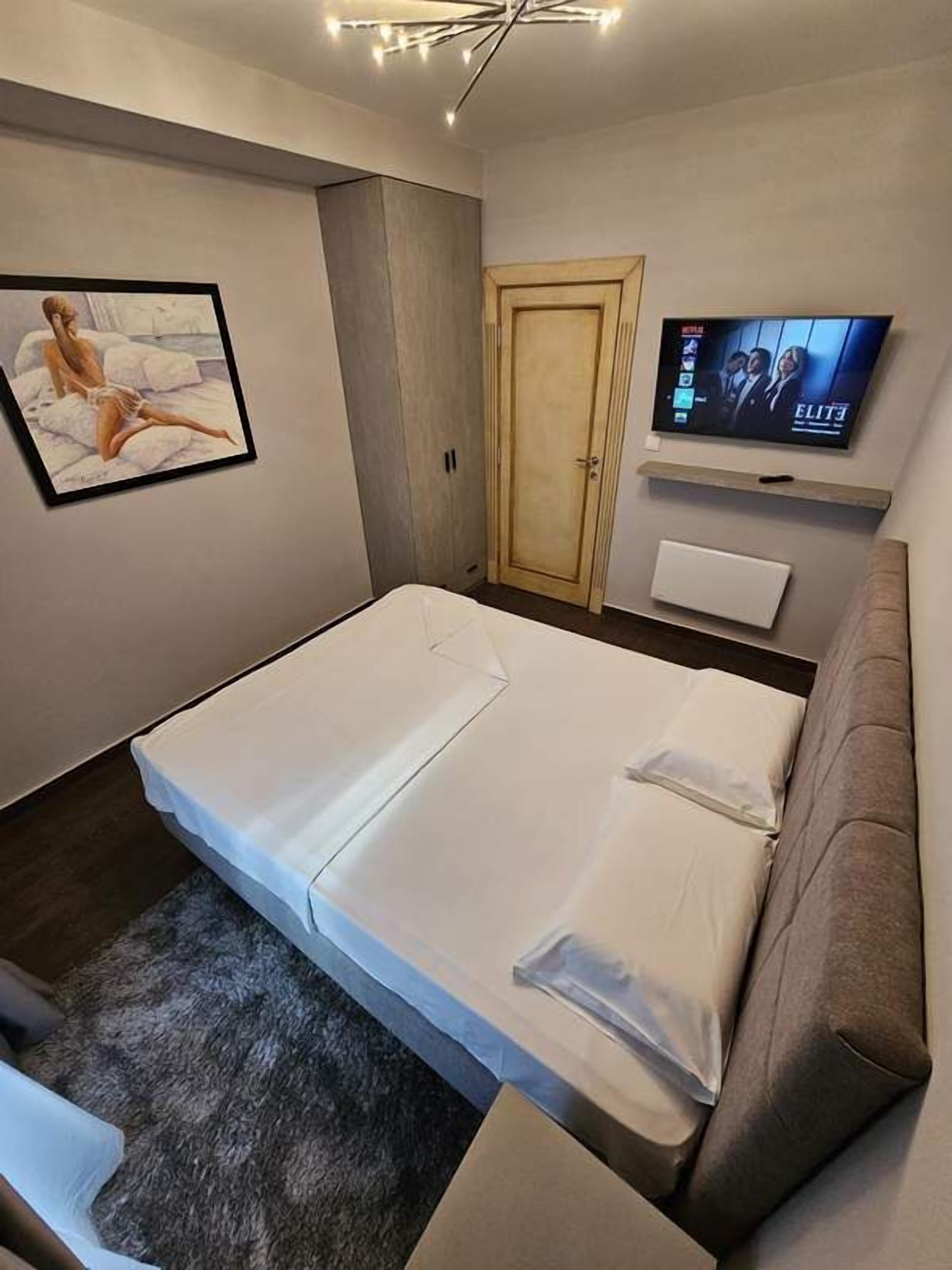 Un dormitorio moderno con una cama, un televisor, un armario y un cuadro en la pared.