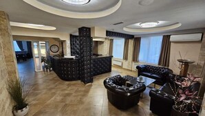 Un hall d’entrée spacieux, doté d’un comptoir de réception noir, de sièges en cuir et d’un design de plafond moderne.