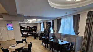 Un hall d’hôtel spacieux, doté d’un piano, de coins salon et d’un téléviseur.