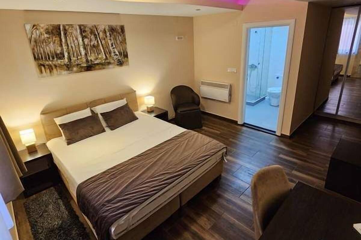 Moderni hotellihuone, jossa on suuri sänky, yöpöydät, työpöytä ja tuoli.