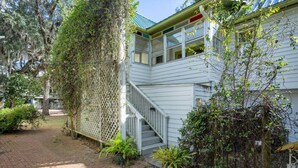 A house with a covered porch, a staircase leading to a second floor, and a brick pathway.
