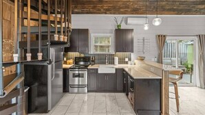 Une cuisine moderne avec des meubles de couleur sombre, des appareils électroménagers en acier inoxydable et un plan de travail en marbre.
