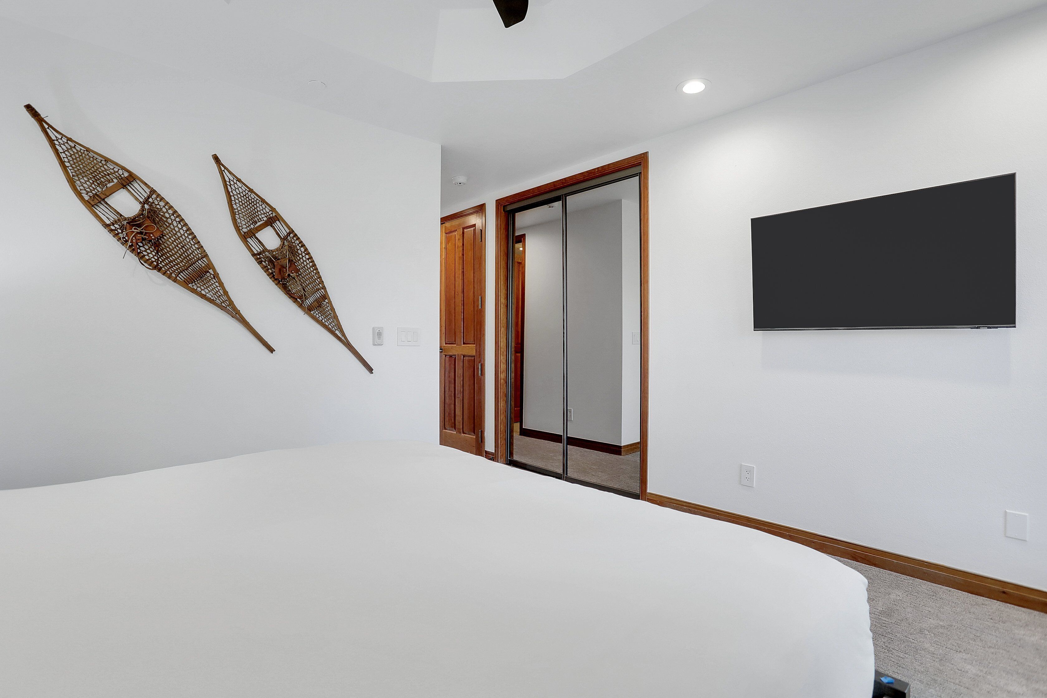 Un dormitorio con una cama grande, un armario y un televisor de pantalla plana en la pared.