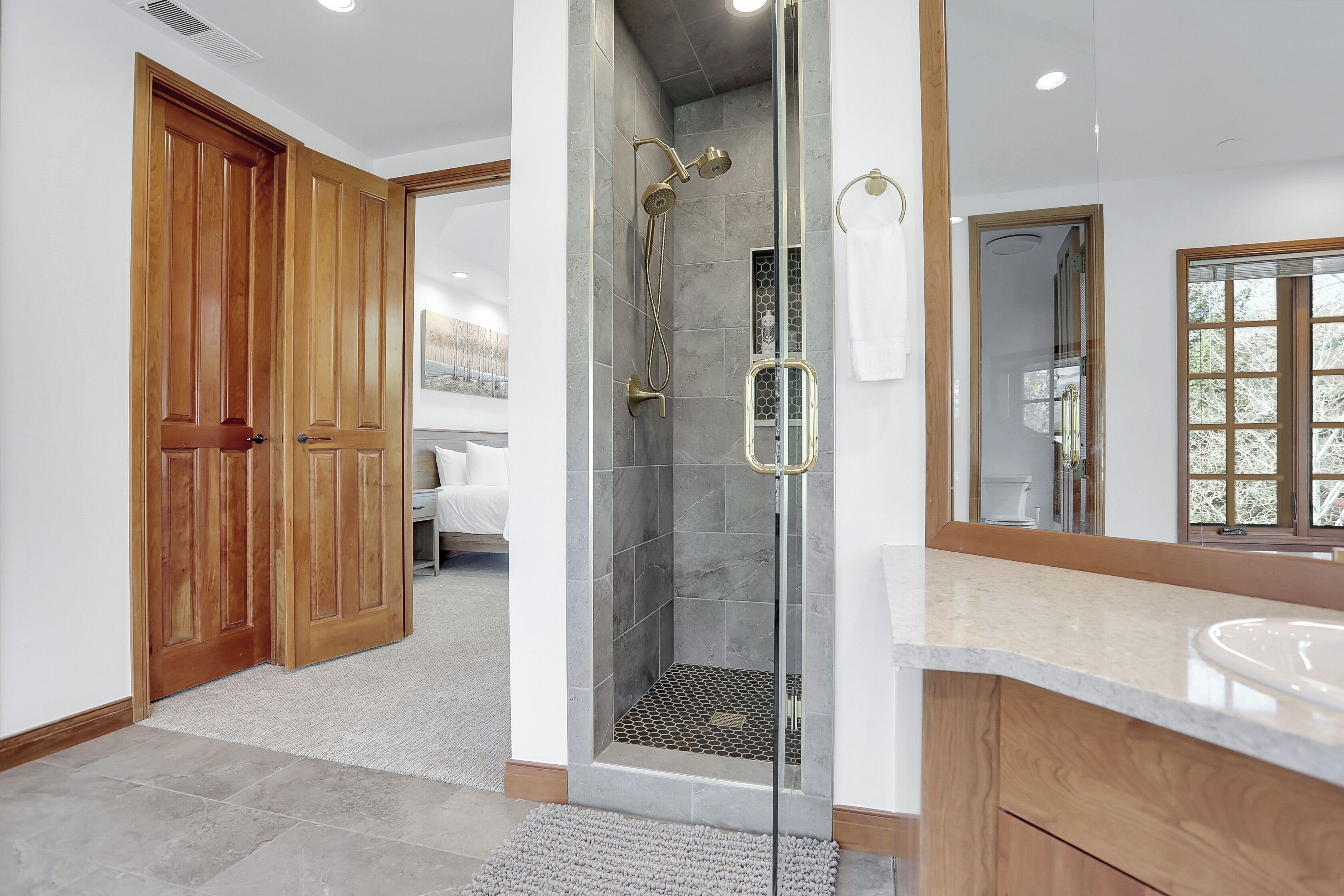 Un baño moderno con ducha de vidrio, puertas de madera y un espejo grande.