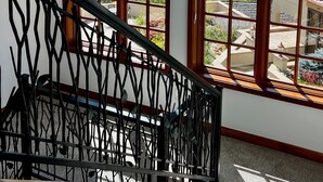 Un escalier avec une rampe noire menant à un palier doté de grandes fenêtres qui offrent une vue sur un paysage montagneux.