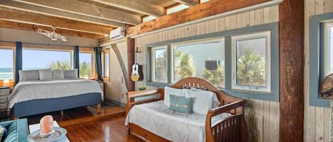 Une chambre confortable, aménagée dans le style d’un chalet, avec deux lits, un plancher en bois, de grandes fenêtres et une guitare.