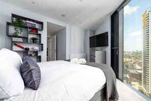 Une chambre moderne avec un grand lit, une télévision et une vue sur la ville.