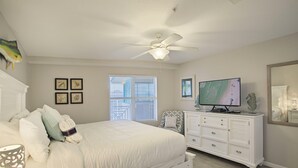 Ein Schlafzimmer mit Bett, Kommode, Fernseher und Deckenventilator.