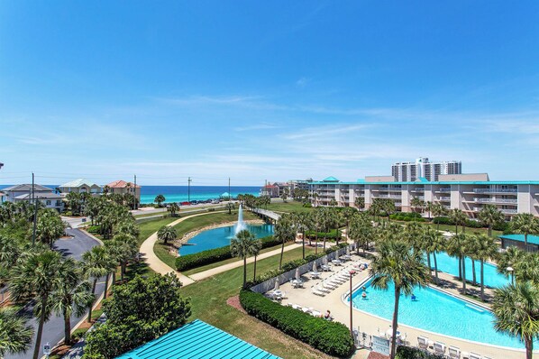 Un resort con varias piscinas, un puente y vista al océano.