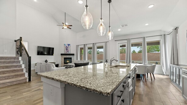 A spacious kitchen with a large island, modern pendant lights, and a view of the outdoors.