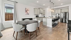 A modern kitchen with grey cabinets, stainless steel appliances, and a central island with bar stools.