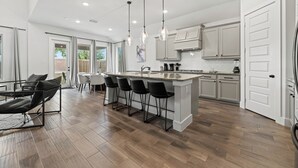 A modern kitchen with a central island, bar stools, and pendant lighting.