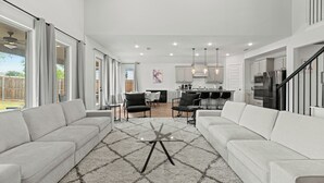 A spacious living room with a large sectional sofa, a glass coffee table, and a dining area with a bar.
