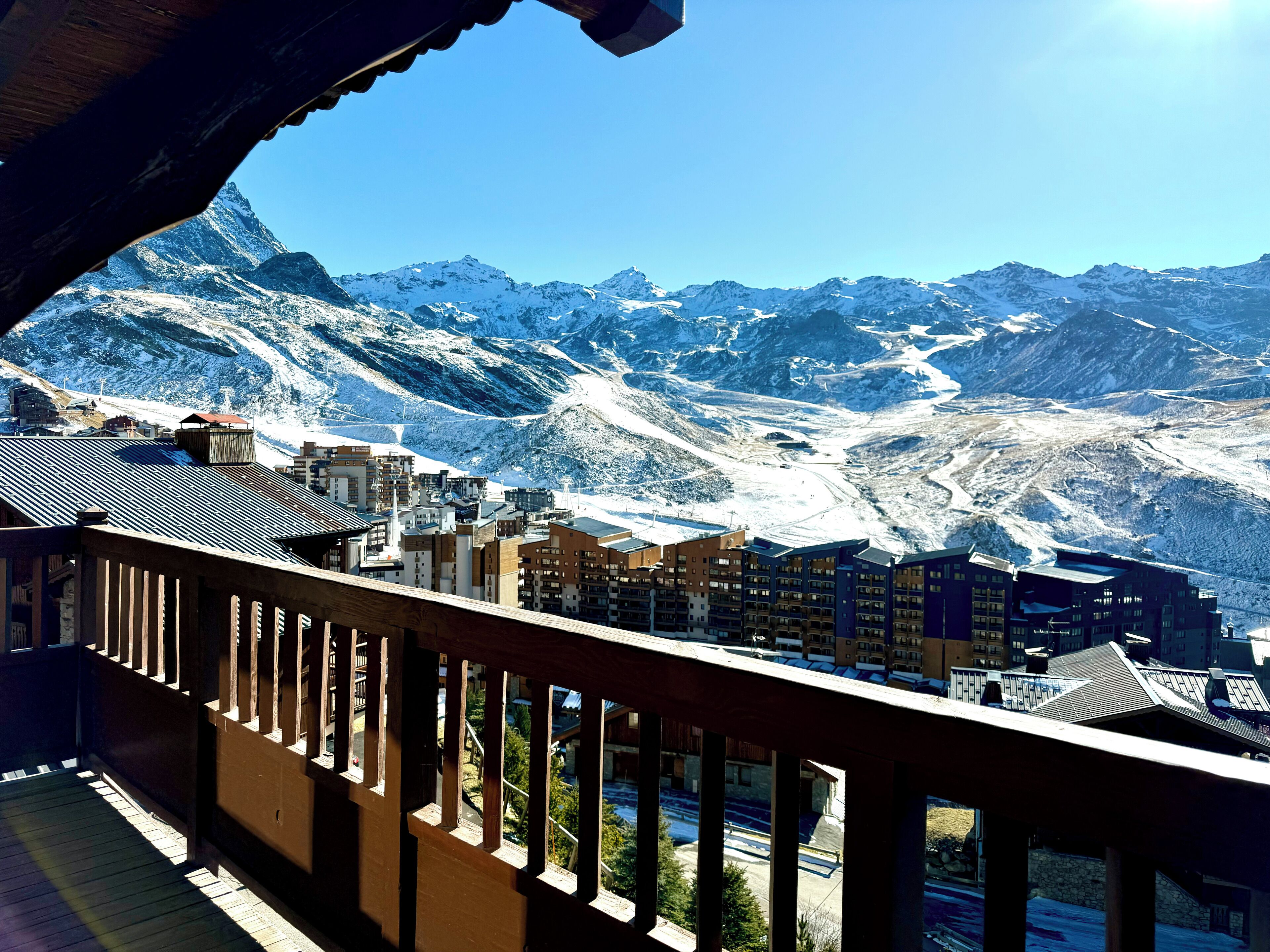 A mountain view from a balcony with buildings in the foreground.