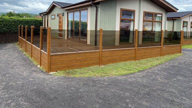 A two-story house with a wooden deck, large windows, and a fenced outdoor area. - Tranquil Lodge Retreat in Wells (Wells)