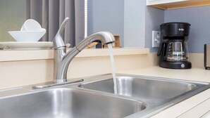 A modern kitchen with a stainless steel sink, a coffee maker, and a bowl on the counter.