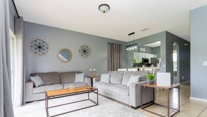 A modern living room with a grey sofa, a wooden coffee table, and a white rug.