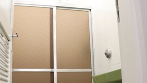 A small bathroom with a green toilet, a white sink, and a brown door. - Apto 422 Ed. São Lucas (Praia Grande)