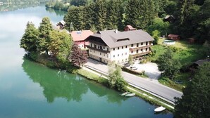 Un hotel a orillas del lago con un edificio grande, una piscina y barcos amarrados cerca del agua.
