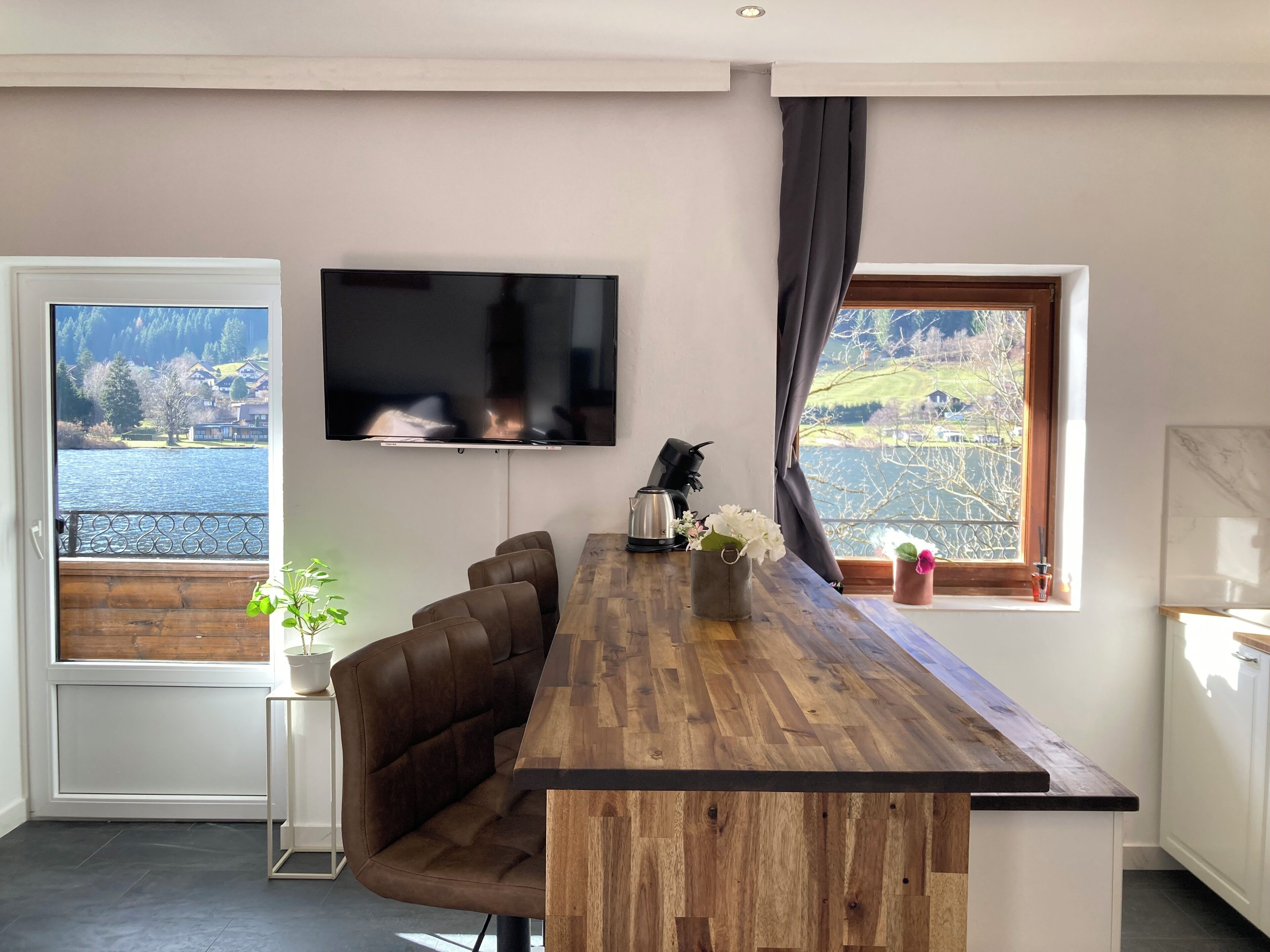 Een moderne keuken met een houten kookeiland, een flatscreen televisie en uitzicht op een meer.