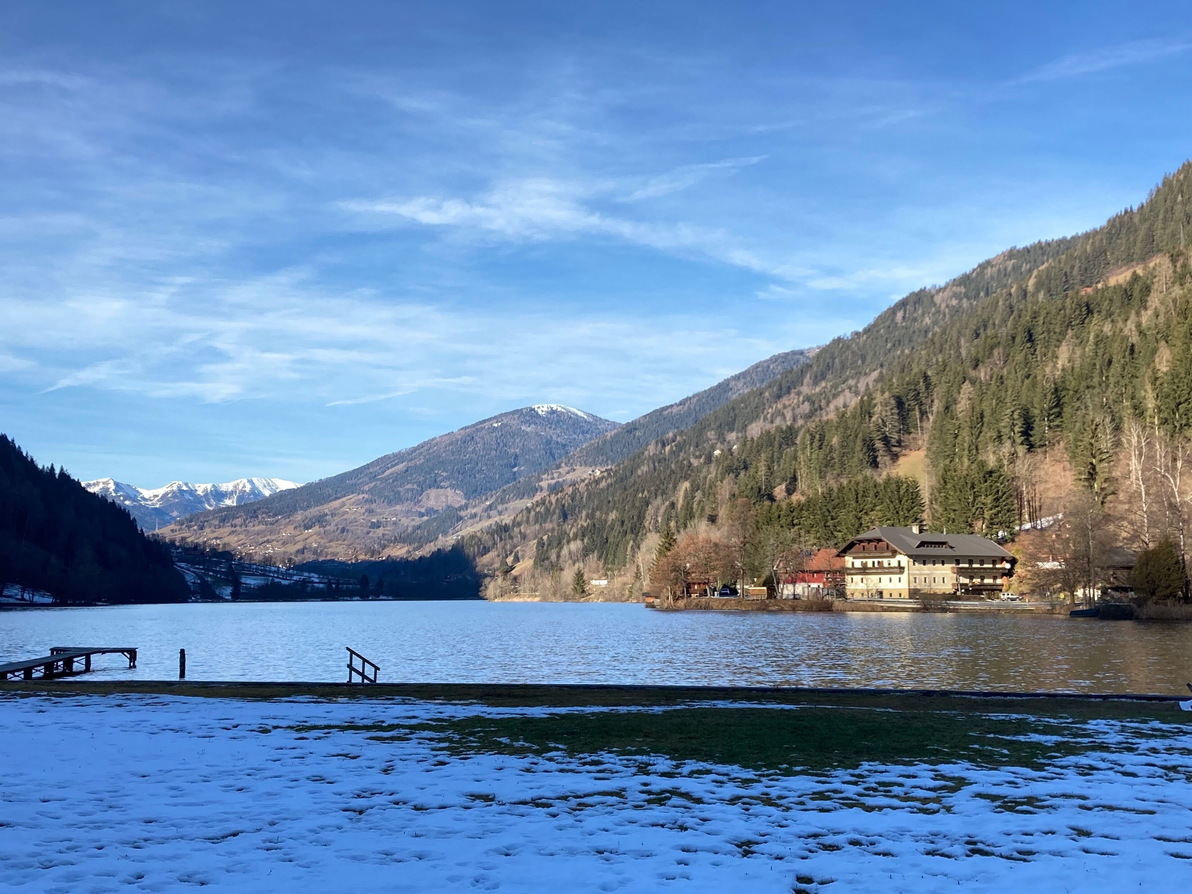 A lakeside view with a building featuring a balcony and a dock.