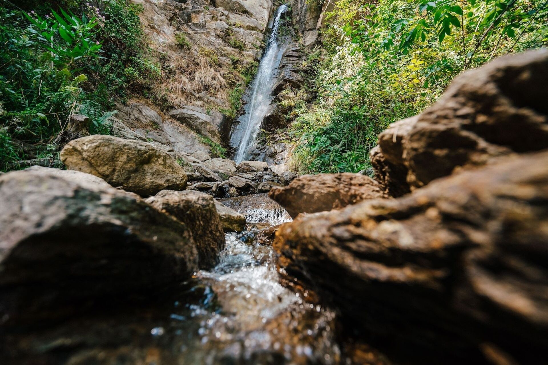 Una cascada natural rodeada de rocas y follaje.