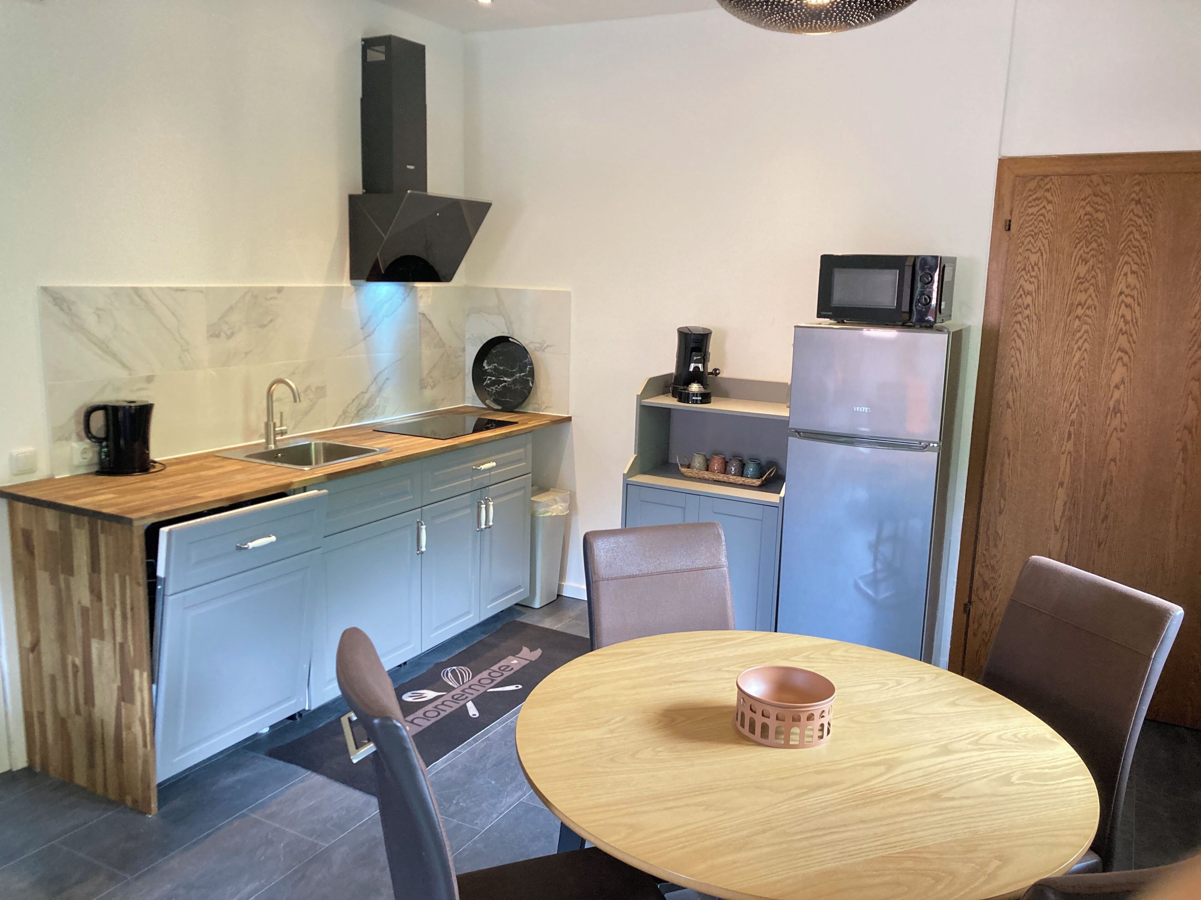 Cocina compacta con lavamanos, estufa y microondas. Hay una zona de comedor con mesa y sillas.