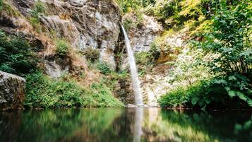 A waterfall cascading into a calm lake surrounded by rocky cliffs and lush greenery.