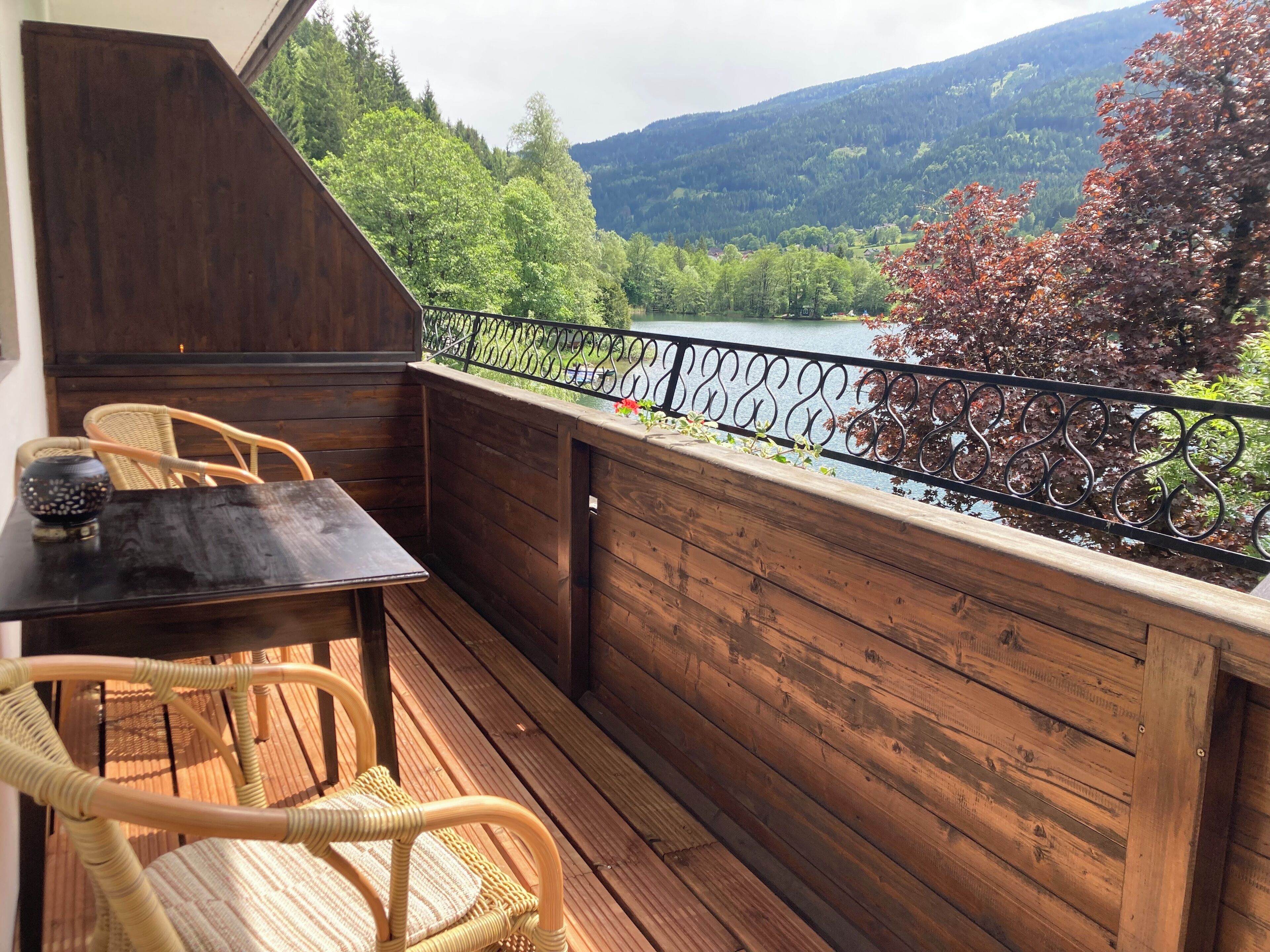 A wooden deck with a table and chairs, overlooking a river and forested hills.