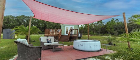 Un espace patio aménagé avec du mobilier d’extérieur, un jacuzzi et une terrasse couverte.
