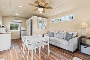 Un espacio habitable compacto con kitchenette, zona de comedor, sofá y ventilador de techo.