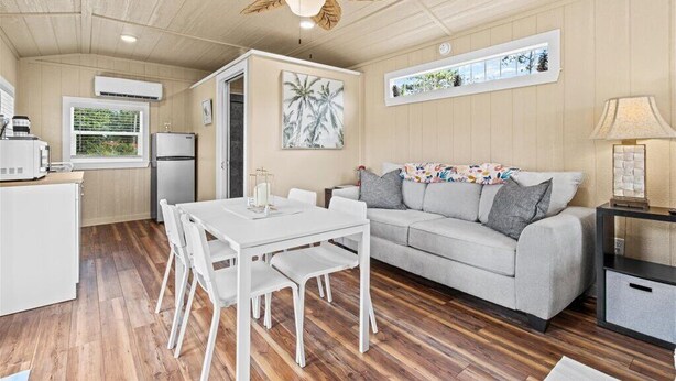 Un espacio habitable compacto con una mesa de comedor, un sofá, un ventilador de techo y una zona de cocina.