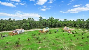 Una propiedad rural con dos cabañas pequeñas y un extenso campo cubierto de césped.