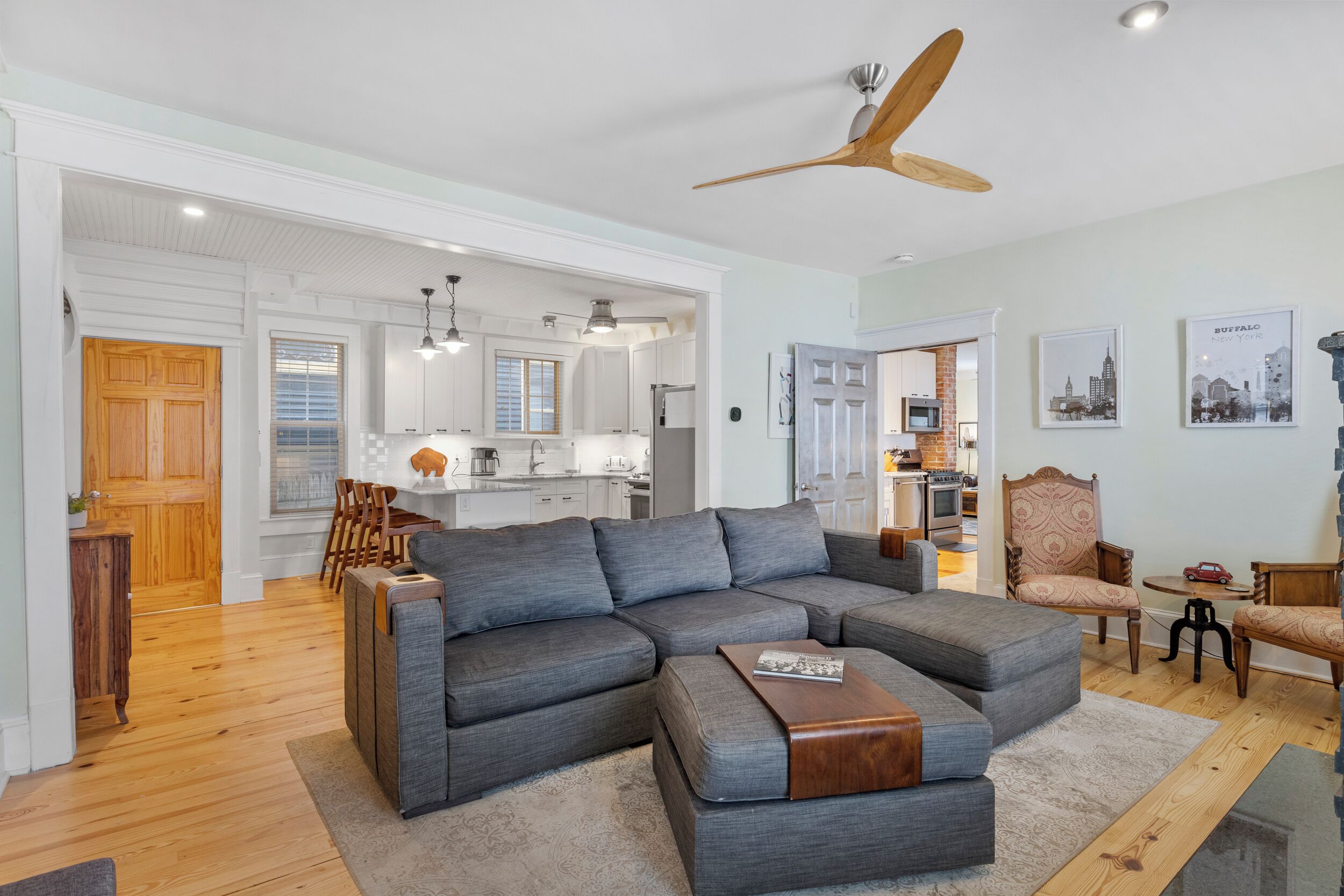 A modern living room with a sectional sofa, a wooden coffee table, and a ceiling fan.