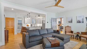 A modern living room with a sectional sofa, a wooden coffee table, and a ceiling fan.