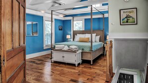 Un dormitorio con una cama con dosel, un aparador de madera y un cuadro en la pared.