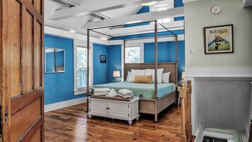A bedroom with a four-poster bed, a wooden dresser, and a framed picture on the wall.