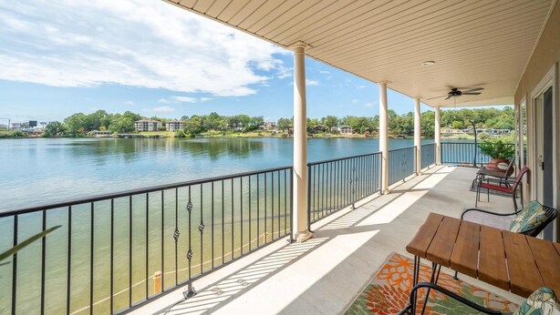 A covered balcony with a view of a lake, a table, and chairs. - Lakefront home away from home! (Hot Springs)