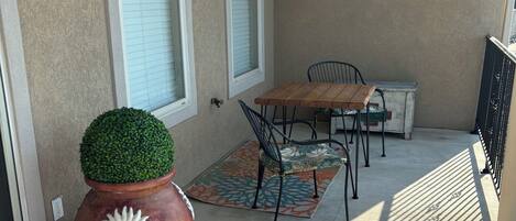 A patio with a table and chairs, a potted plant, and a patterned rug.