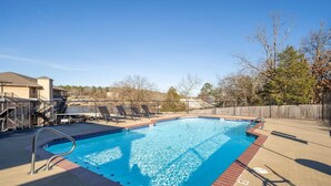 A swimming pool with a metal ladder, surrounded by a deck with lounge chairs and a wooden fence. - Lakefront home away from home! (Hot Springs)
