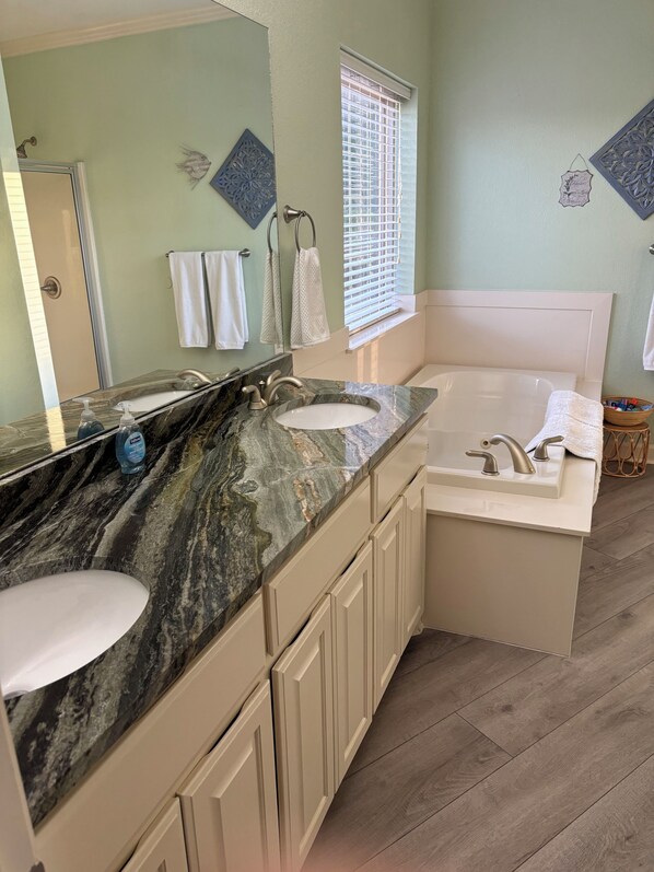 A bathroom with a marble vanity, a bathtub, and a large mirror. - Lakefront home away from home! (Hot Springs)