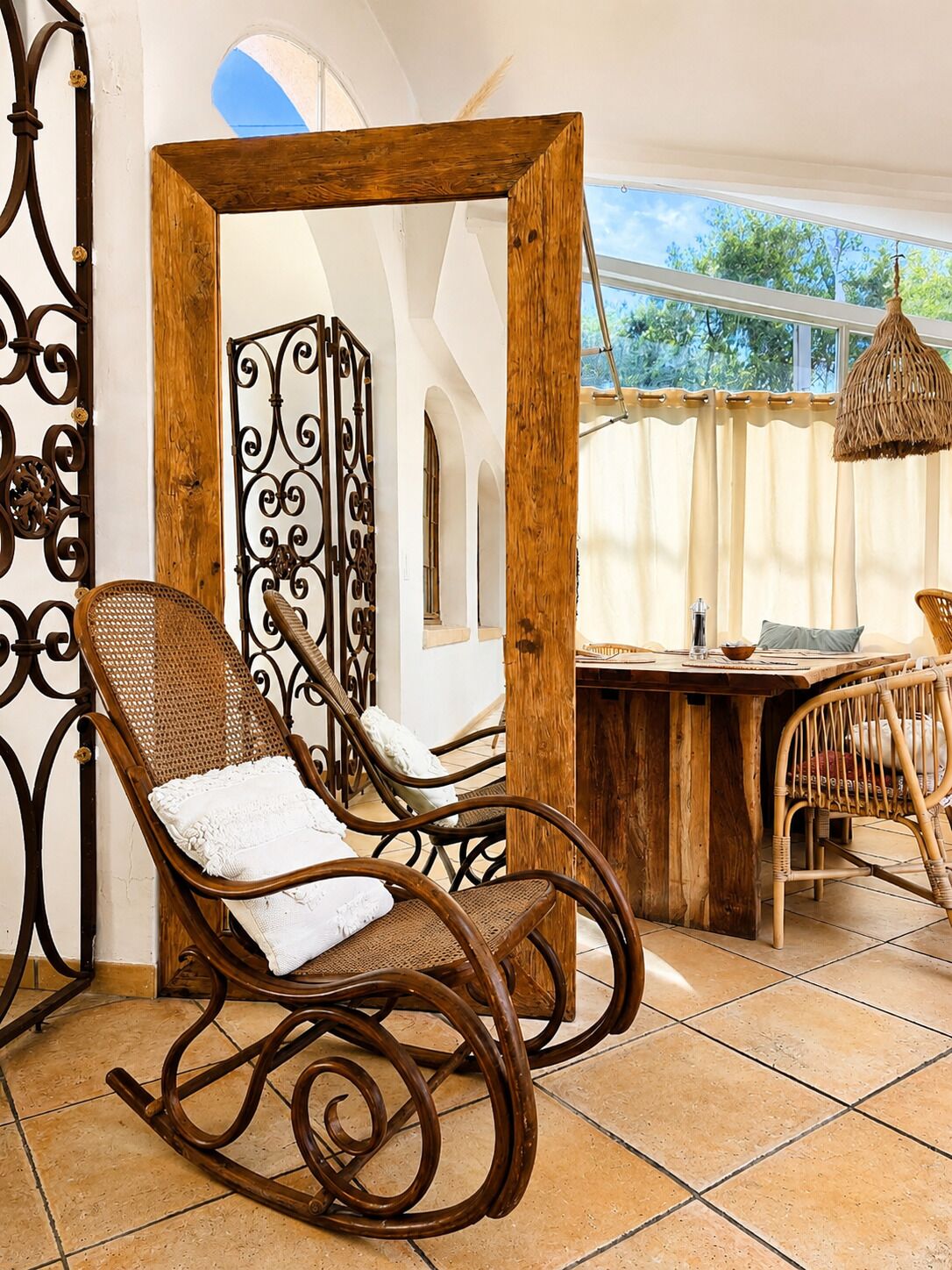 A rustic interior with a rocking chair, wooden table, and wrought iron decor.