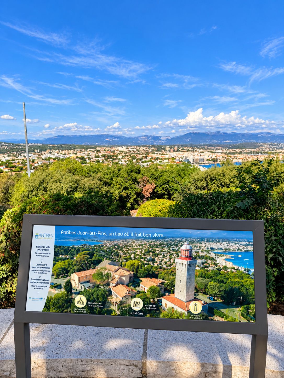 A sign with a view of Antibes Juan-les-Pins, including landmarks like the lighthouse and the port.