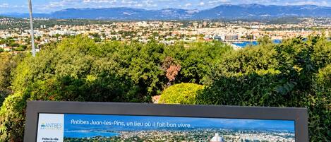 Un cartel muestra vistas de Antibes Juan-les-Pins, incluyendo puntos de referencia como el faro y el puerto.